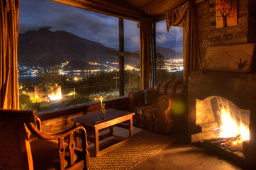 Interior of a cozy cabin at night, with a lit fireplace and a beautiful view of the San Pablo lake and Imbabura volcano, Ecuador.