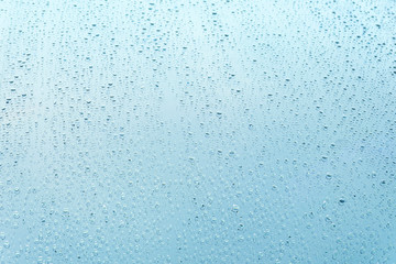 Water drops on glass blue background.