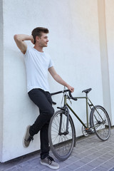 Handsome hipster man posing with bicycle in the city.