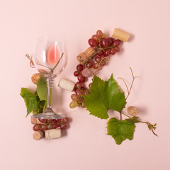 Alphabet. Letter K made of wineglasses with rose and white wine, grapes, leaves and corks lying on pink background. Wine degustation concept. Flat lay. Top view