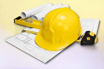 Yellow hard hat and blueprints in a construction concept