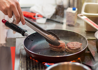 Fry the meat in a frying pan. Chef preparing and spicing meat restaurant kitchen