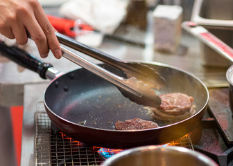 Fry the meat in a frying pan. Chef preparing and spicing meat restaurant kitchen