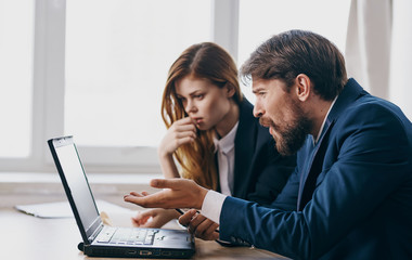 man and woman working on laptop in an office