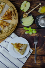 Piece of apple galette on the plate served with cinnamon and honey