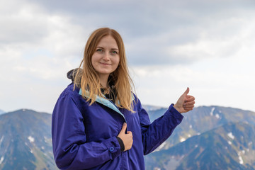 Woman feeling happy making a thumbs up with her hands against on mountain rocks landscape background
