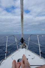 Fototapeta na wymiar Couple feet on sailboat with sea view