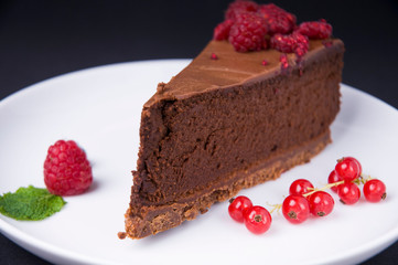 Piece of chocolate cheesecake with berries on dark background