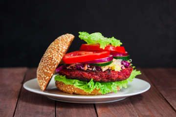 healthy vegetarian burger with beet patty coleslaw salad cucumber tomato lettuce on plate on dark wooden background 