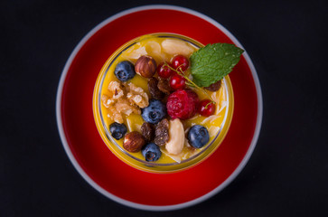  A glass of yogurt with blueberries and mango mousse, forest berries, granola and mint leaf