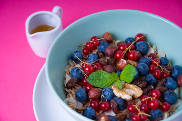 Oatmeal cereal porridge with fresh berries and nuts. Healthy breakfast. Top view on pink table