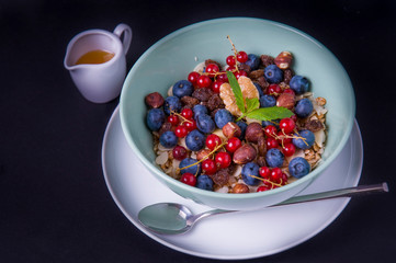 Oatmeal cereal porridge with fresh berries and nuts. Healthy breakfast. Top view on black table