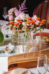Assortment of canapes on wooden board. Balls cherry tomatoes, basil, greens on skewers, a wooden spaska. Appetizer, caprese. Catering food iIsolated on white background. Party food concept.