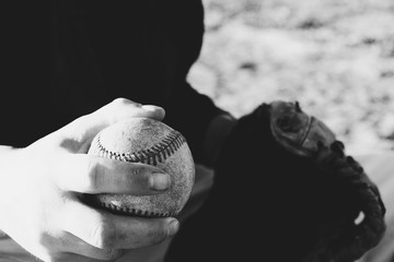Baseball player sitting with ball and glove in black and white, athlete lifestyle.