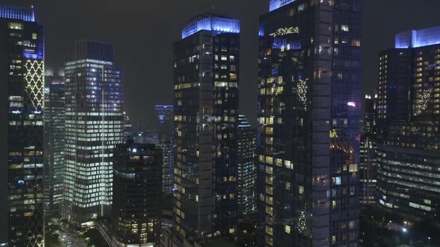 JAKARTA, Indonesia - July 09, 2019: Aerial view of silhouette of modern office buildings and apartment in central business district at night. Shot in 4k resolution from a drone flying forwards