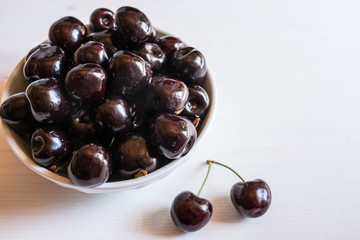 close of fresh organic summer ripe black cherries in a white porcelain bowl room for text  fileld frame 