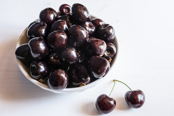 close of fresh organic summer ripe black cherries in a white porcelain bowl room for text  fileld frame 
