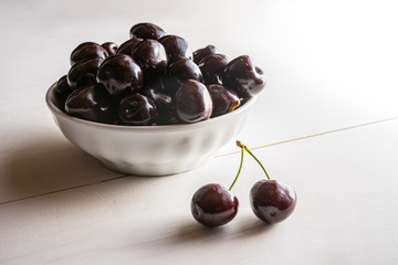 close of fresh organic summer ripe black cherries in a white porcelain bowl room for text  fileld frame 