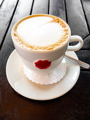 tasty white cup of cappuccino with latte art on wooden table.