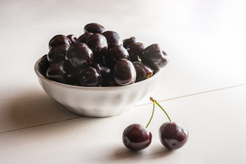 close of fresh organic summer ripe black cherries in a white porcelain bowl room for text  fileld frame 
