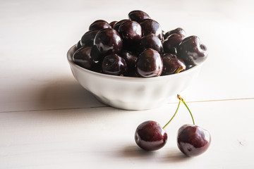 close of fresh organic summer ripe black cherries in a white porcelain bowl room for text  fileld frame 