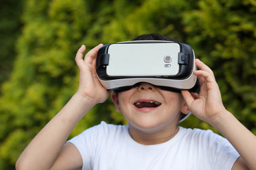 Cute little boy using VR glasses outdoors in a park - Blogger testing augmented reality goggles concept - Gamer exulting during 3D video game playing 