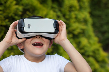 Cute little boy using VR glasses outdoors in a park - Blogger testing augmented reality goggles concept - Gamer exulting during 3D video game playing 