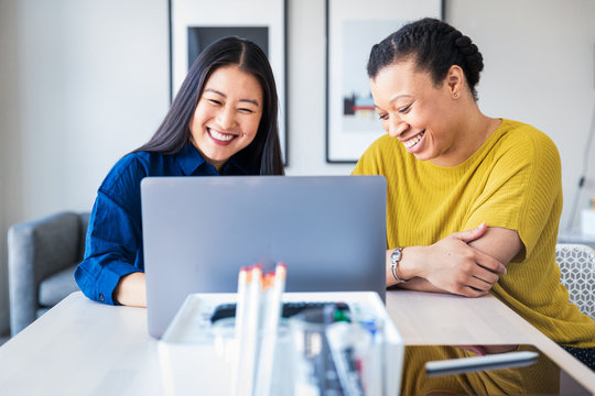 Two business colleagues smiling in front of laptop