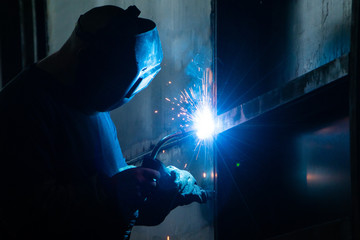 Welder in his workshop welding metal, lots of sparks flying around