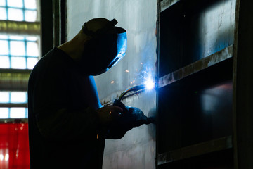 Welder in his workshop welding metal, lots of sparks flying around