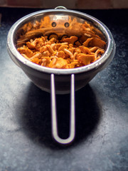 Yellow chanterelle (cantharellus cibarius) in a pot on a table surface.
