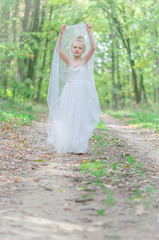 adorable child in long white wedding dress in dreamy atmosphere