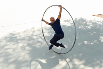 Cyr wheel acrobat stretching in a park outdoors