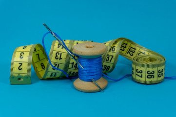 Blue thread, tape measure and sewing needle