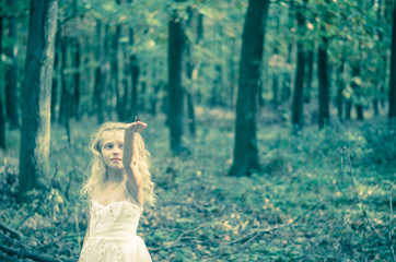 adorable child in long white wedding dress with butterfly in hands