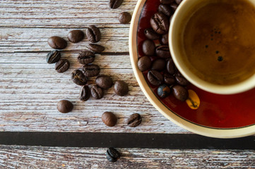 Tazza di caffè con grani sparsi sul tavolo di legno 