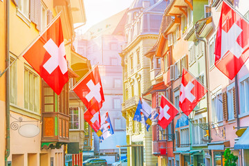 Old street with old colorful buildings with bay window balconies decorated with national flags, Zurich, Switzerland