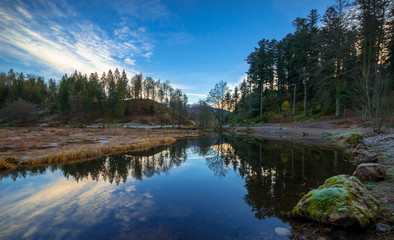 Fototapeta na wymiar Nonnenmattweiher im Schwarzwald beim Sonnenaufgang und Spiegelung im stillen Wasser im Herbst
