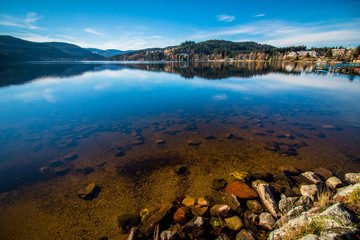 Titisee im Schwarzwald blauer Himmel und stillem reflektierendem Wasser mit Spiegelung der Berge