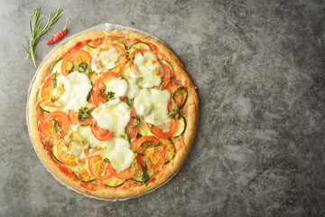 Vegetarian pizza made with wholegrain dough, with zuchinni, tomatoes and mozarella cheese. Healthy, dietical pizza. Top view.