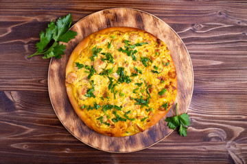 homemade pizza with meat and cheese and vegetables on a wooden table