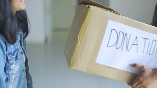 Donation concept. Young woman giving a donation cardboard box on a man. Shot in 4k resolution