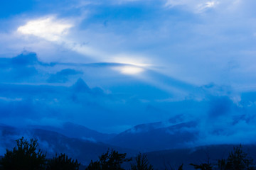 Sun streaking through clouds over a mountain range, Stowe, Vermont, USA