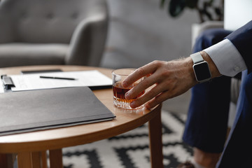 Documents on the table and hand putting glass of alcohol there
