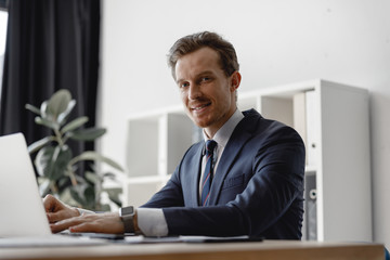 Fototapeta premium Young businessman looking at the camera while sitting in the office