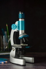 Back to school. Microscope isolated on black background. Studying biology at school laboratory.