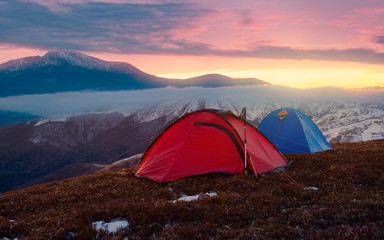 Tourist camping in autumn mountains. Two tents on nacbkground of sunrise