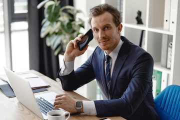 Confident businessman with his smartphone and laptop