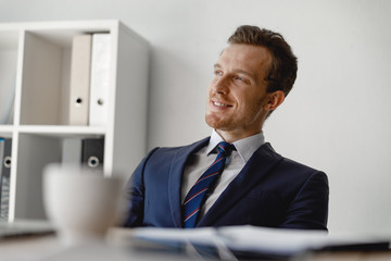 Naklejka premium Cheerful man in suit and tie looking away and smiling