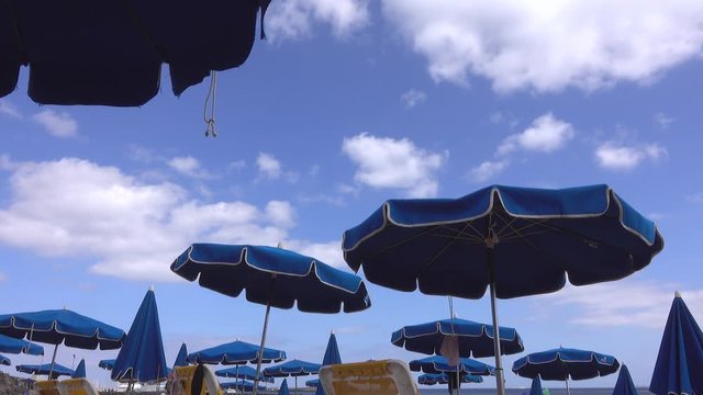 : Windblown blue parasols on the beach at Playa Dorada on the South coast of the Spanish island of Lanzarote. 